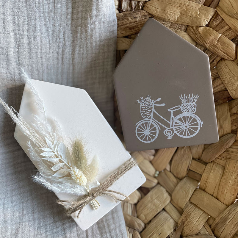 bunte Hausmodelle mit einem Fahrradaufdruck und Trockenblumen