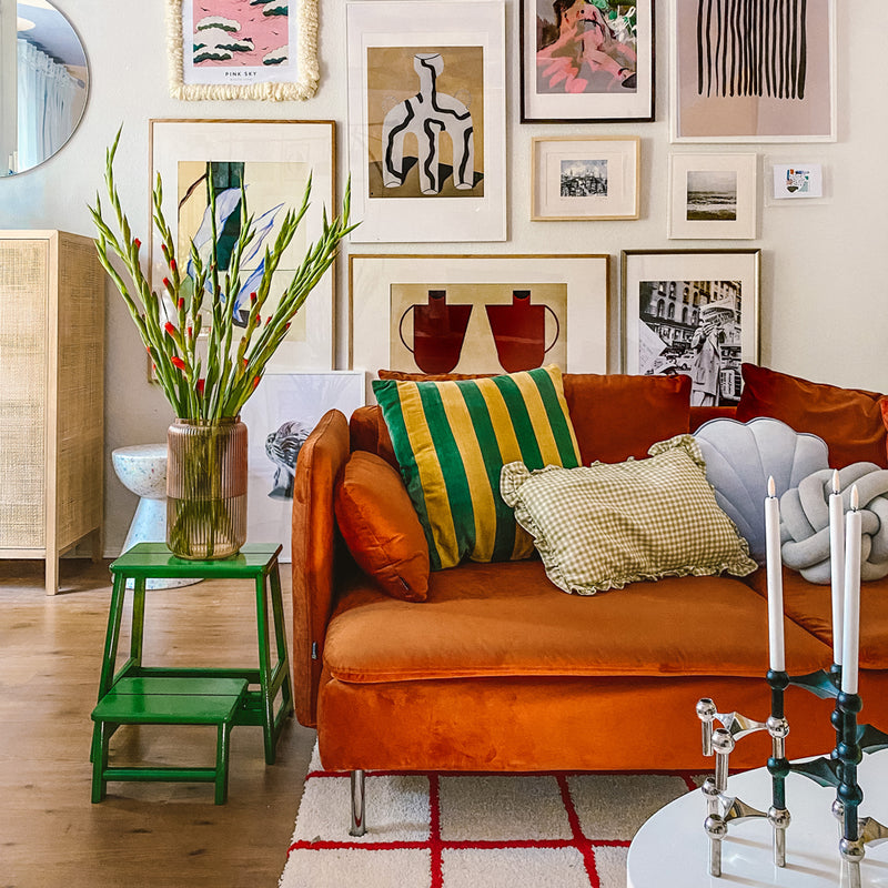 grüner Hocker neben einem orangefarbenen Sofa