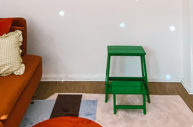 grüner Hocker neben einem orangefarbenen Sofa