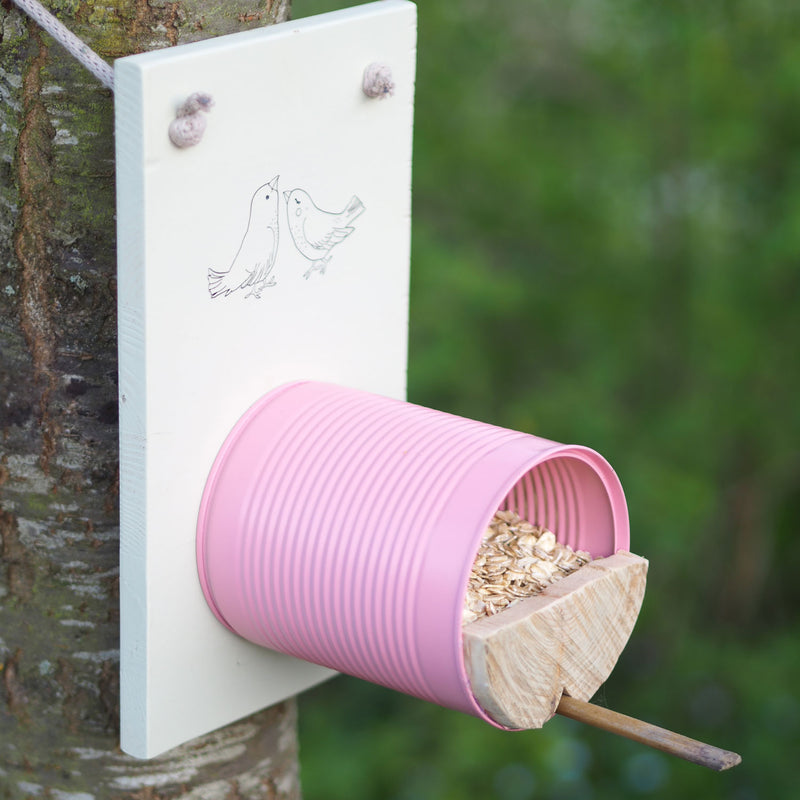 Selbstgebautes pinkes Vogelhaus mit Holzbrett am Baum
