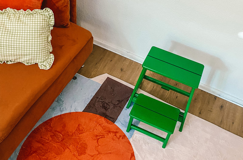 grüner Hocker neben einem orangefarbenen Sofa