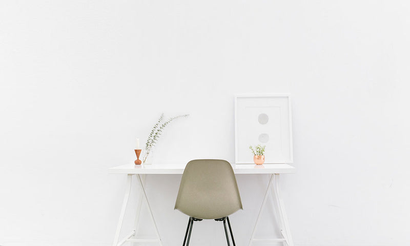 weißer Schreibtisch mit Stuhl vor einer weißen Wand